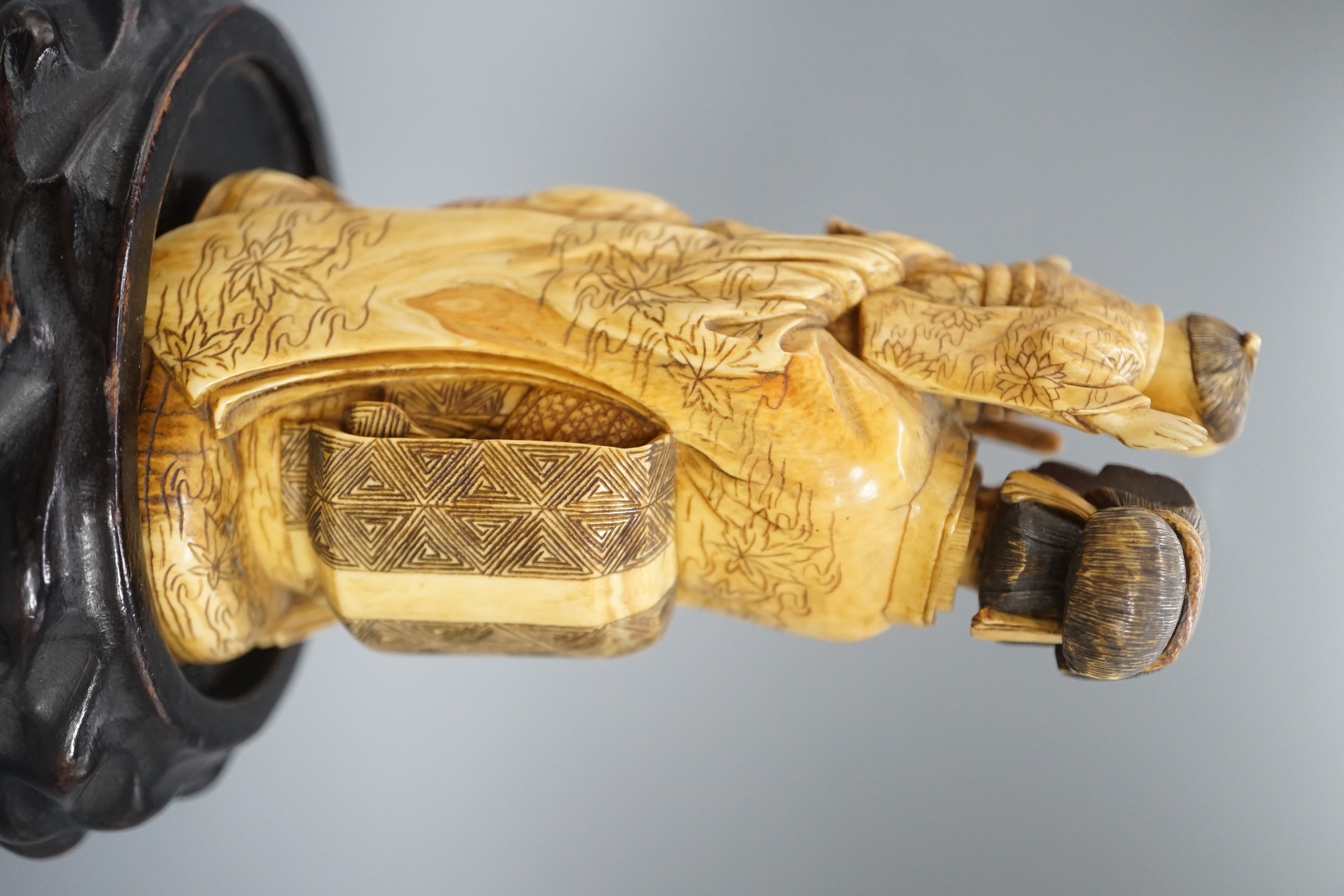 A Japanese ivory okimono of a lady holding a boy with a bow and arrow, Meiji period, restoration 12cm, wood stand